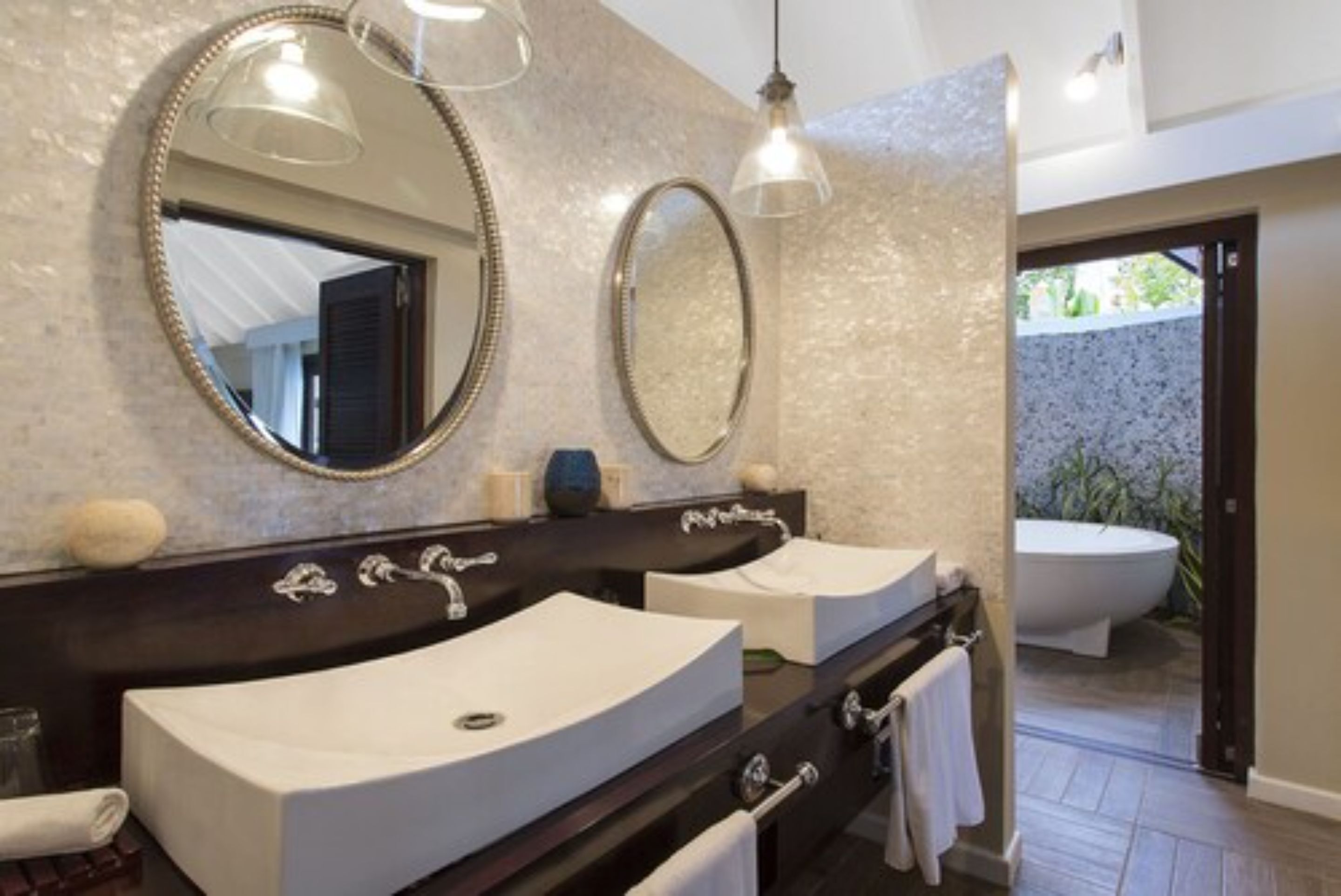 A bathroom with two sinks, a large mirror, and a freestanding bathtub.