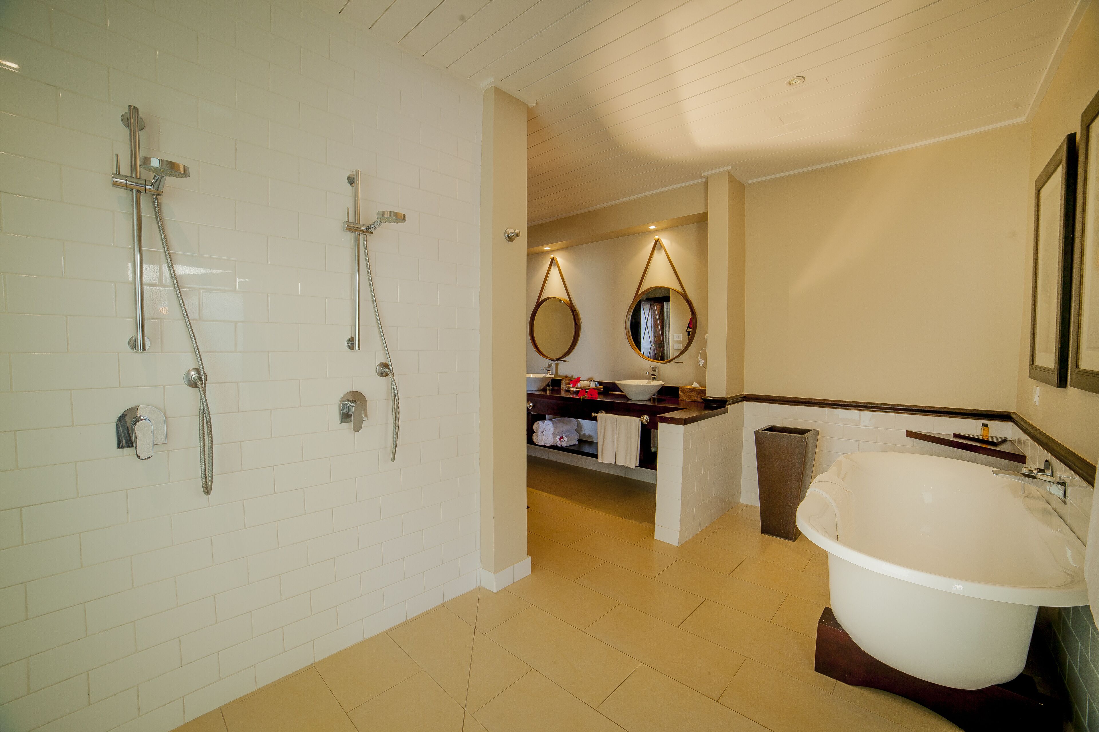 Un baño moderno con una bañera independiente, una ducha con cabezal de ducha manual y dos espejos adosados a la pared.