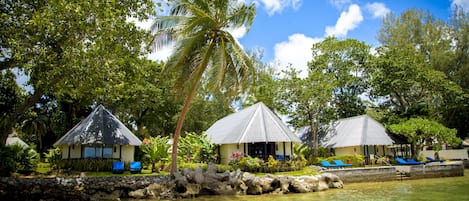 A resort with multiple bungalow-style buildings, a palm tree, and a clear blue sky.