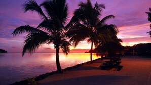 A beach scene with palm trees and a sunset over the water. - Warwick Le Lagon - Vanuatu (Port Vila)