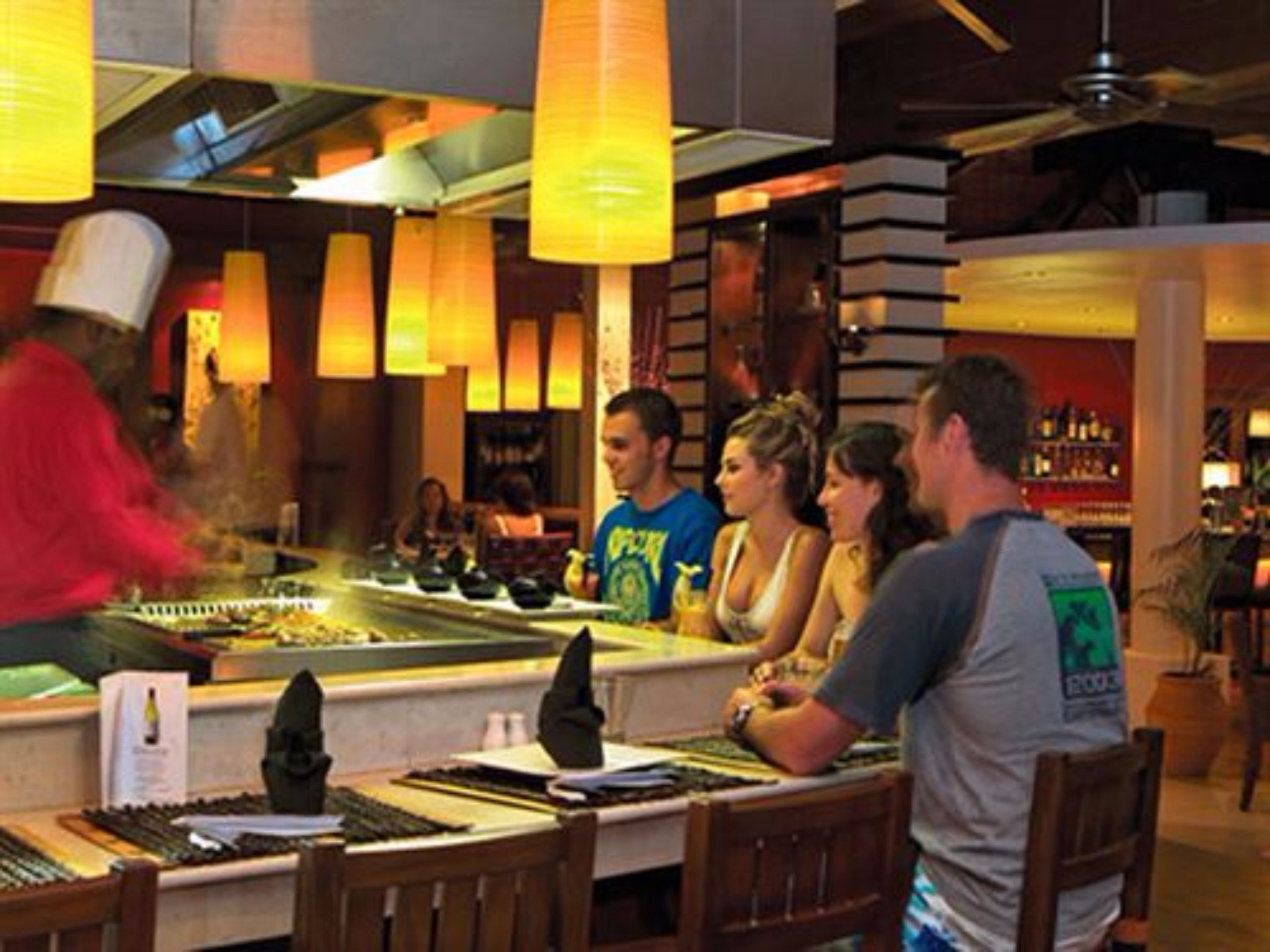 A restaurant with a bar area, tables, and hanging lights.
