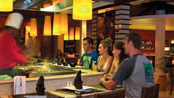 A restaurant with a bar area, tables, and hanging lights.