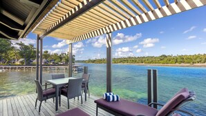 A wooden deck with outdoor seating and a view of a calm body of water. - Warwick Le Lagon - Vanuatu (Port Vila)