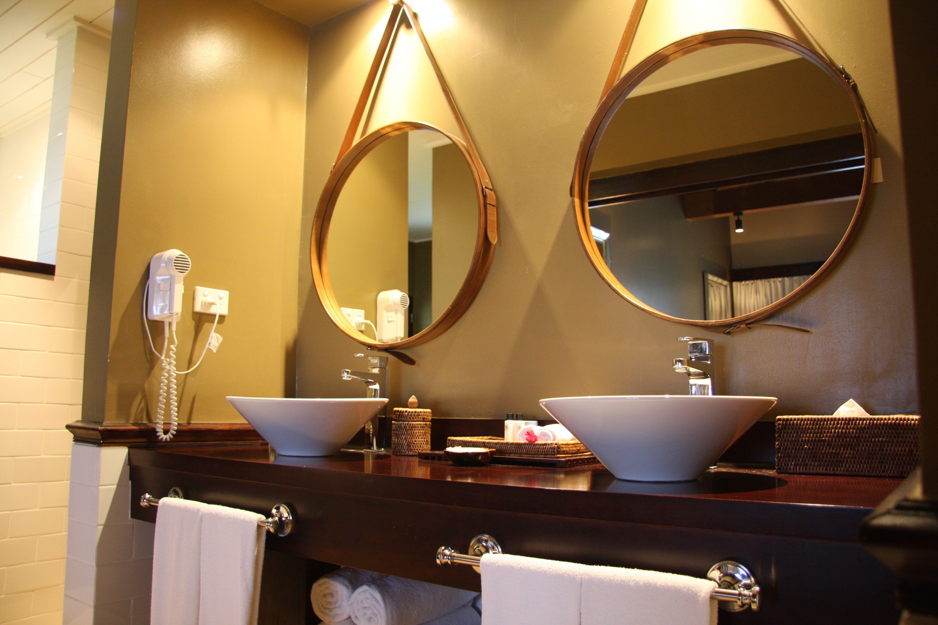 A bathroom with two sinks, a hairdryer, and two mirrors.