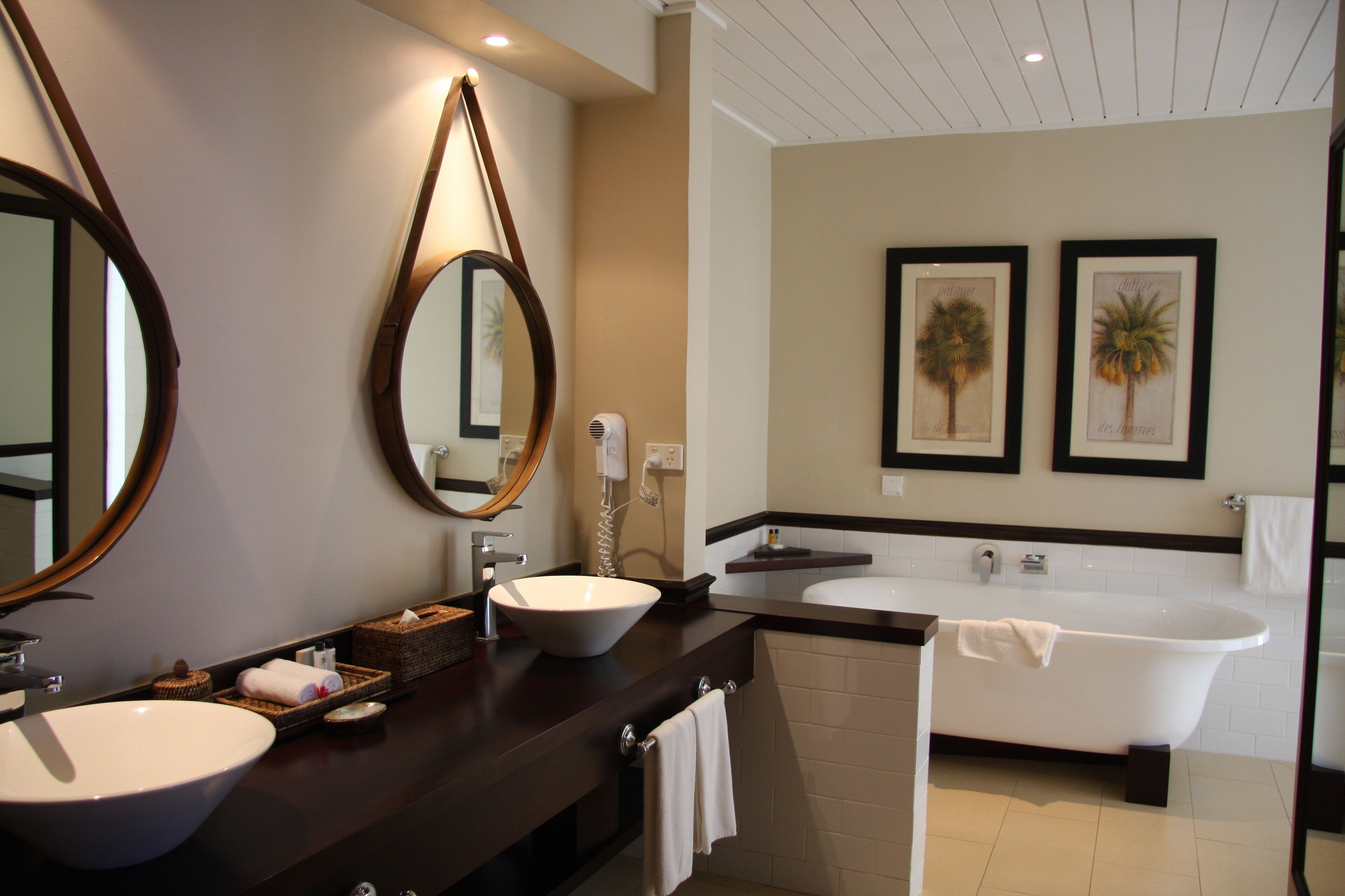A modern bathroom with two sinks, a large mirror, and a bathtub.