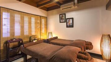 Two single beds with brown bedding, a wooden ceiling, and a large window with bamboo shades.