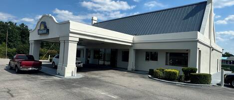 A Days Inn with a covered parking area, a red truck parked outside, and a clear blue sky.