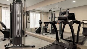 Un gimnasio con equipo cardiovascular, un espejo grande y una cinta de correr.