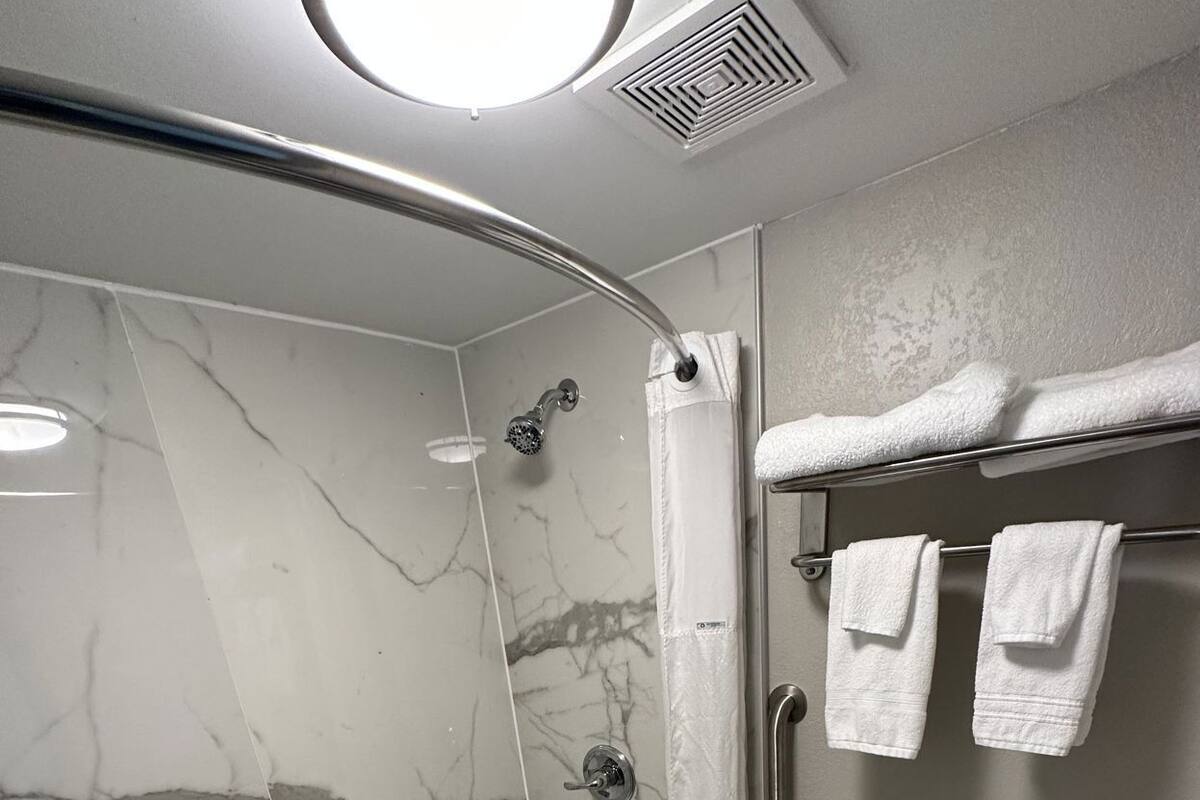 Un baño con ducha de vidrio, inodoro y toallero con toallas.