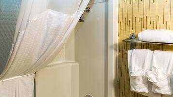 A bathroom with a shower curtain, a bathtub, and a towel rack with towels.