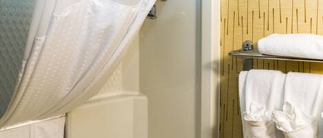 A bathroom with a shower curtain, a bathtub, and a towel rack with towels.
