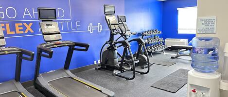 A gym with treadmills, a rowing machine, and dumbbells.