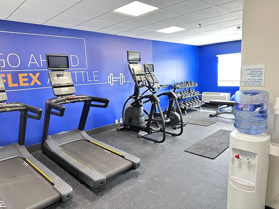 Una palestra con tapis roulant, vogatori e manubri.