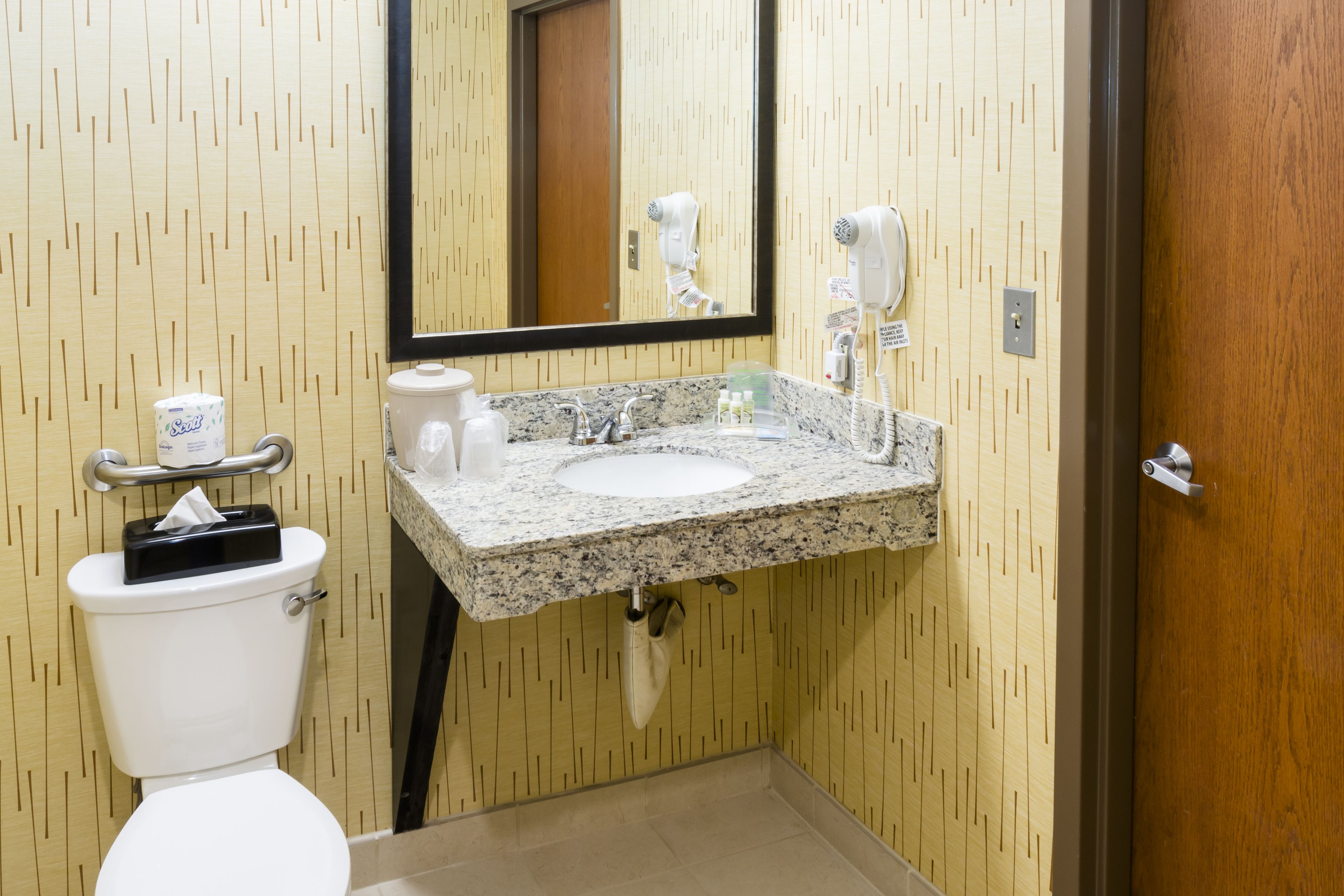 Un bagno con il water, un lavandino e uno specchio.