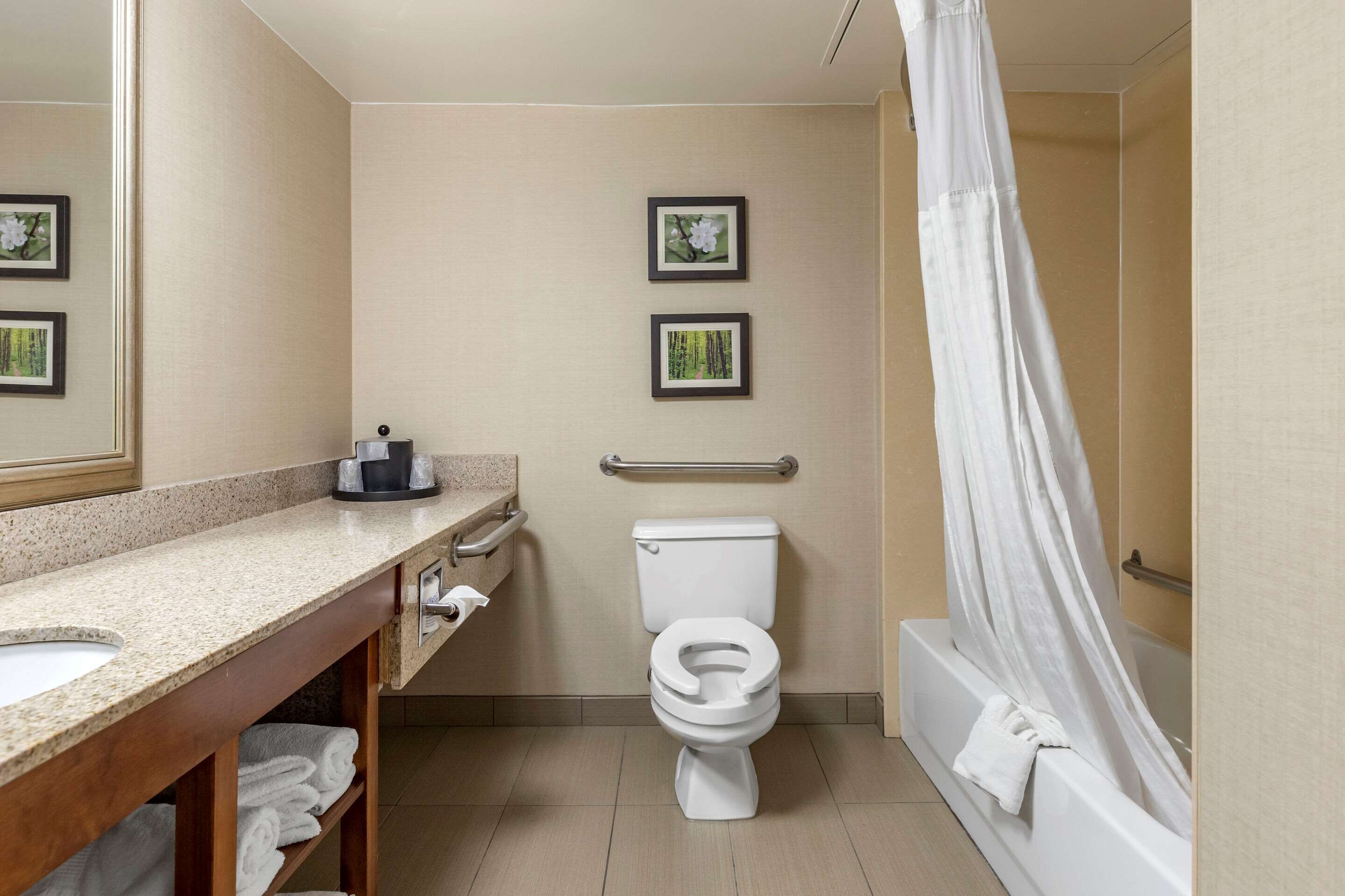 A bathroom with a toilet, sink, and bathtub. There are two framed pictures on the wall.