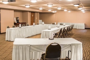 A conference room with long tables, chairs, and a projector screen.