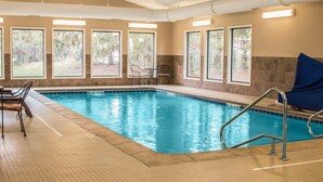 An indoor swimming pool with clear windows, a tiled floor, and a few chairs. - Comfort Inn Lansing West (Lansing)