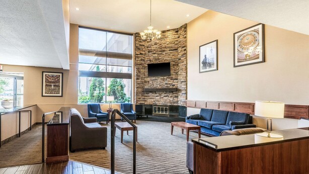 A spacious lobby with a stone fireplace, comfortable seating, and large windows offering views of the outdoors. - Comfort Inn Lansing West (Lansing)