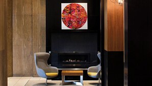 Een moderne woonkamer met een open haard, twee fauteuils en een groot abstract schilderij.