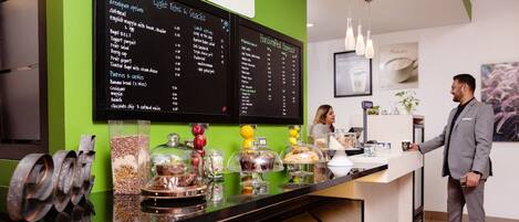 A Starbucks coffee shop counter with a menu board displaying breakfast and lunch options.