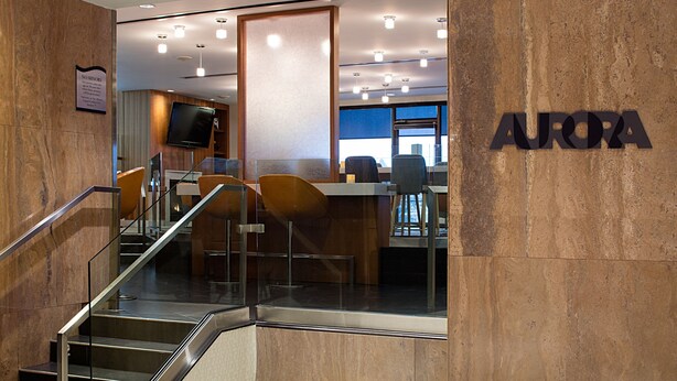 Een moderne hotel lobby met een trap, zithoek en een televisie.