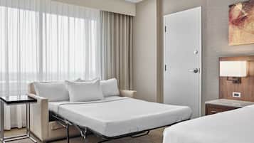 A hotel room with a bed, bedside table, and a desk.