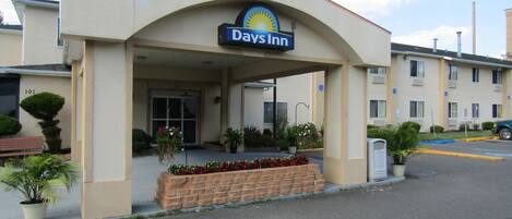 A Days Inn building with a covered entrance, a brick planter with flowers, and a parking lot.