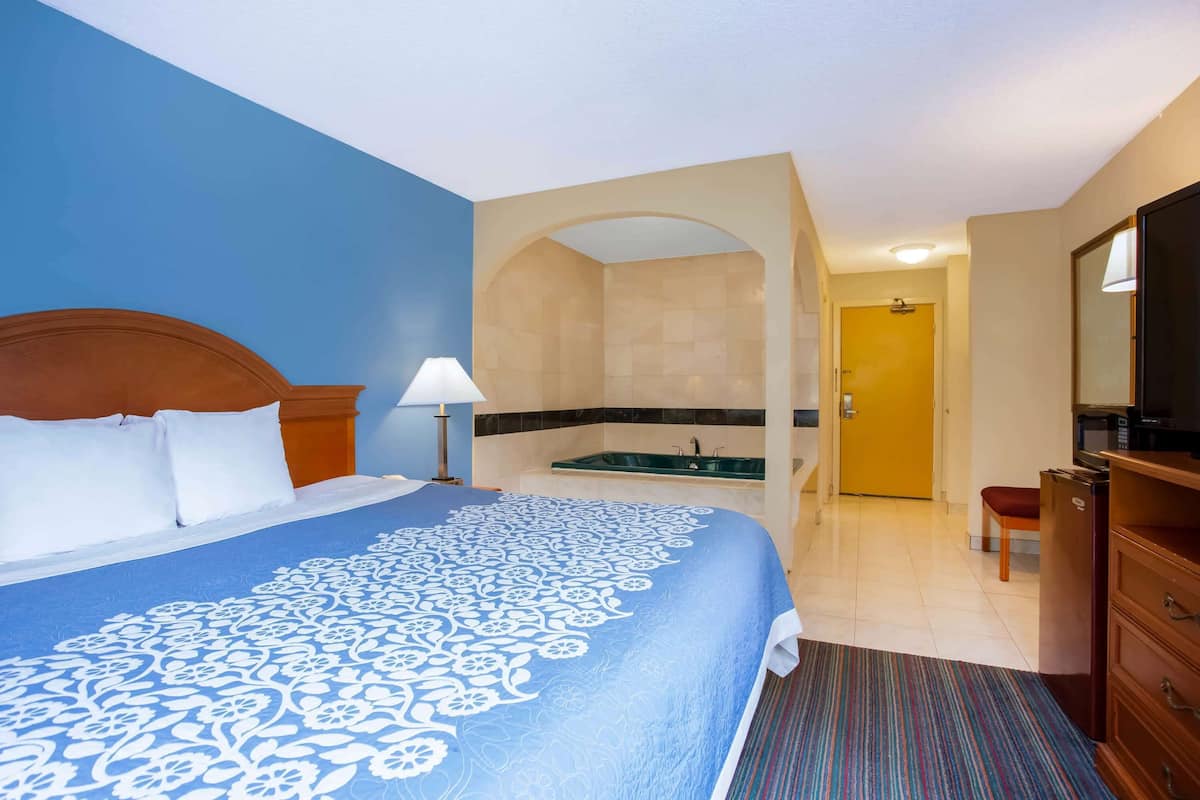 A hotel room with a large bed, a bathroom with a bathtub, and a television.