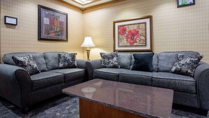 A modern living room with a grey sectional sofa, a wooden coffee table, and framed artwork on the walls. - Days Inn by Wyndham Runnemede Philadelphia Area (Runnemede)