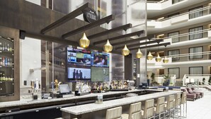 A modern bar area with multiple screens, a variety of liquor bottles, and bar stools. - Embassy Suites by Hilton Atlanta Galleria (Atlanta)