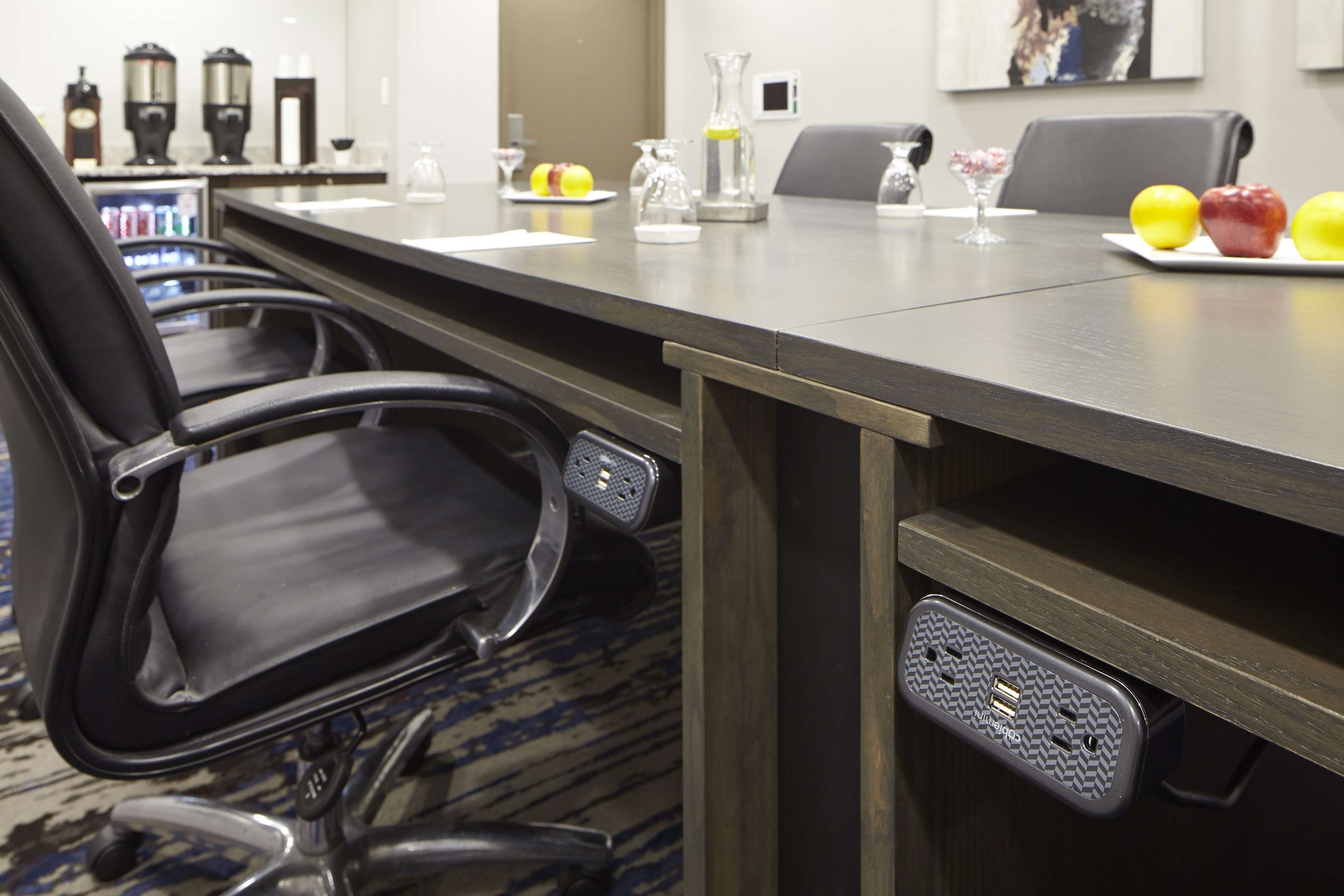 A conference room with a long table, chairs, and a coffee machine.