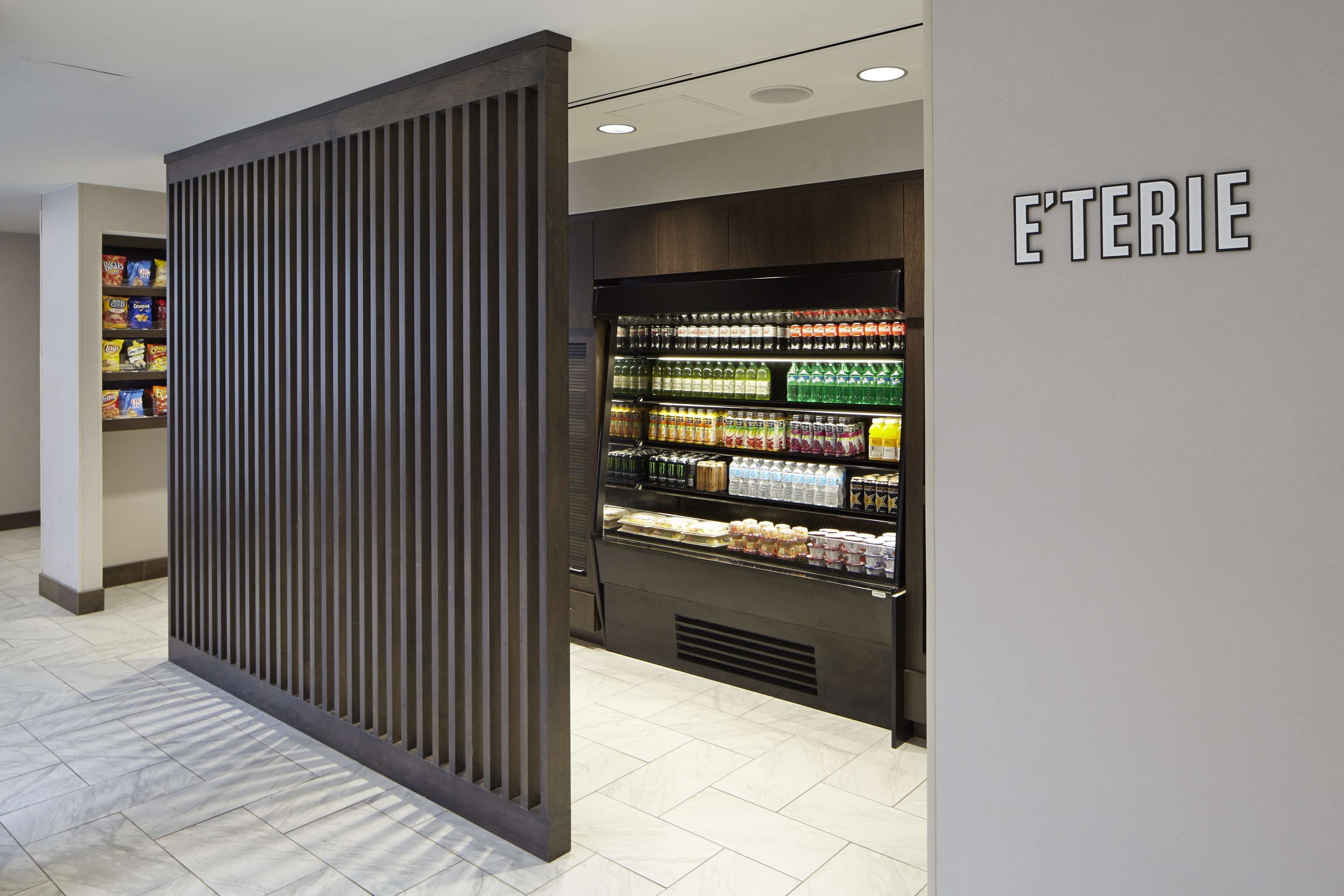 A modern retail space with a refrigerated section labeled "E'TERIE" and a snack shelf.