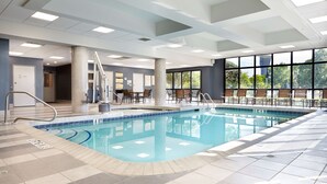A large indoor swimming pool with clear blue water, surrounded by tiled flooring and a seating area with chairs and tables. - Embassy Suites by Hilton Atlanta Galleria (Atlanta)