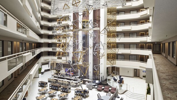 A multi-level atrium with a central open space, multiple dining areas, and a staircase leading to upper floors. - Embassy Suites by Hilton Atlanta Galleria (Atlanta)