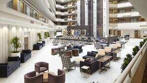 A spacious lobby with multiple seating areas, a bar, and a large screen. - Embassy Suites by Hilton Atlanta Galleria (Atlanta)