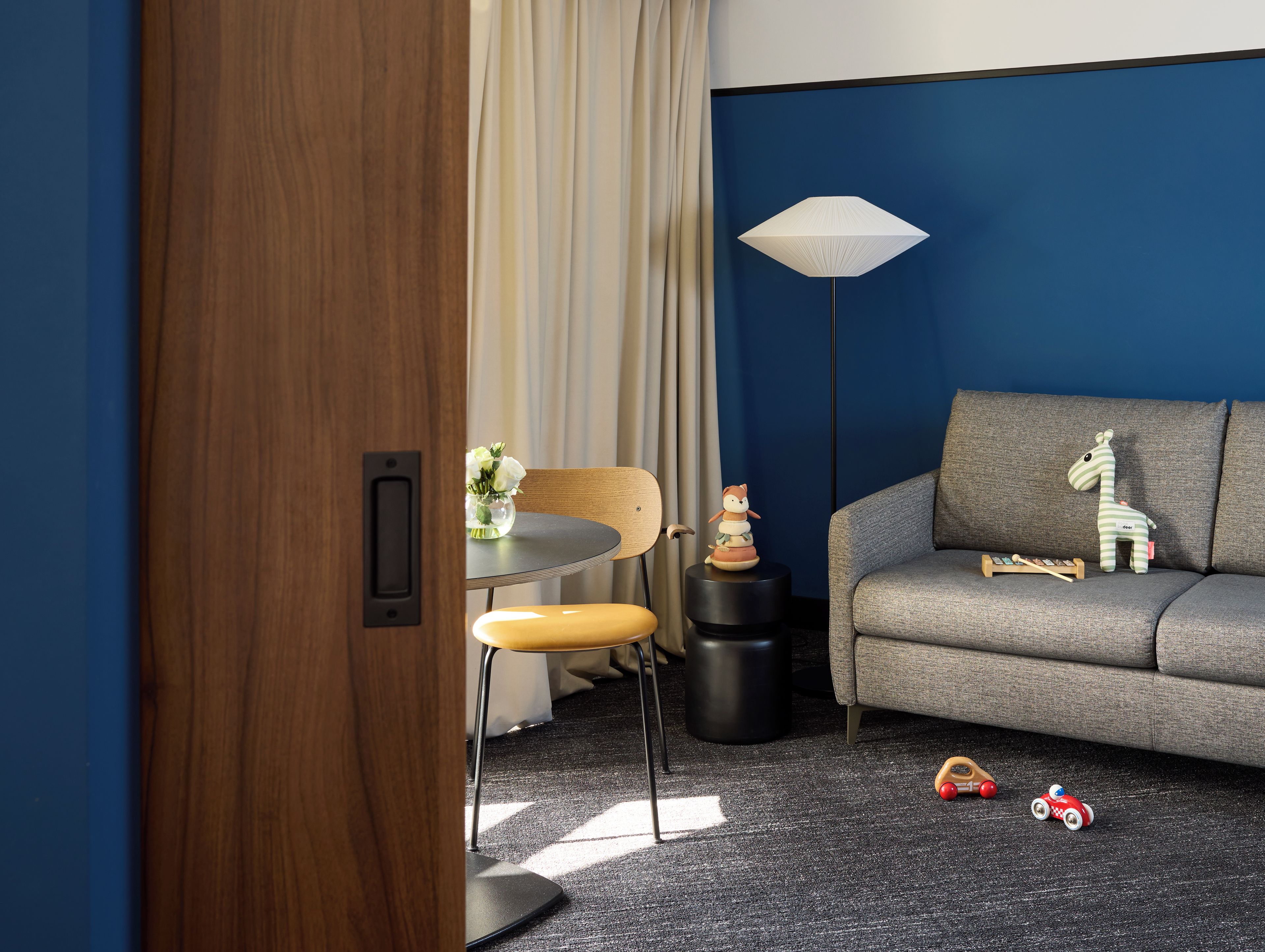 Een moderne woonkamer met een grijze bank, een ronde tafel en een lamp.