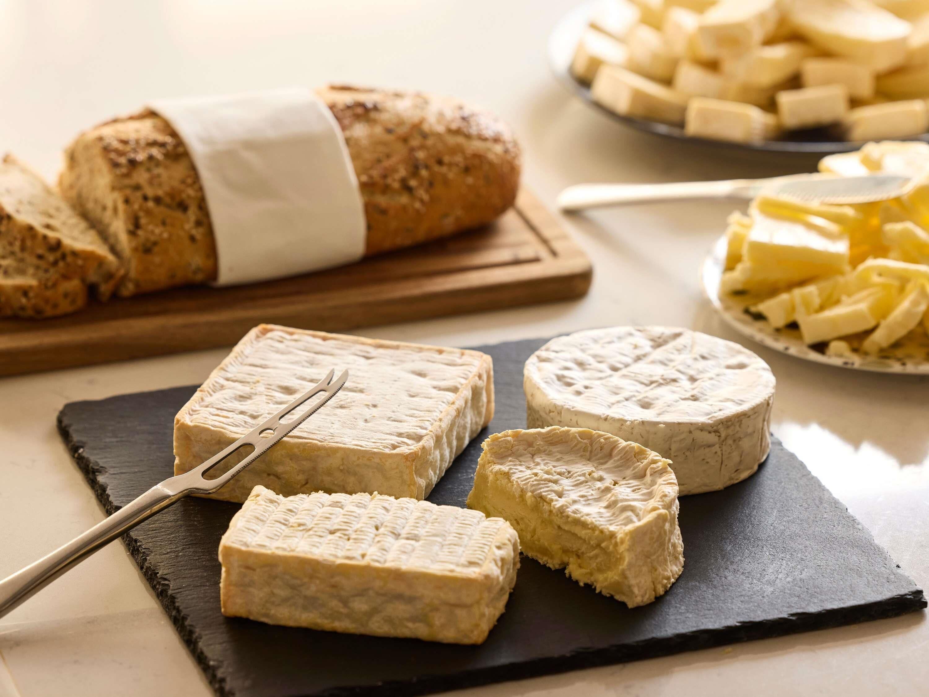A cheese board with various cheeses and a loaf of bread.