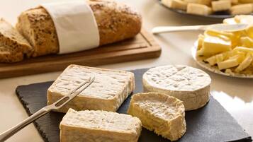 A cheese board with various cheeses and a loaf of bread.