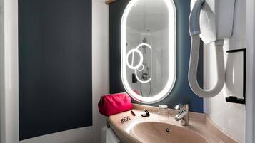 A modern bathroom with a large mirror, a sink, and a hairdryer.