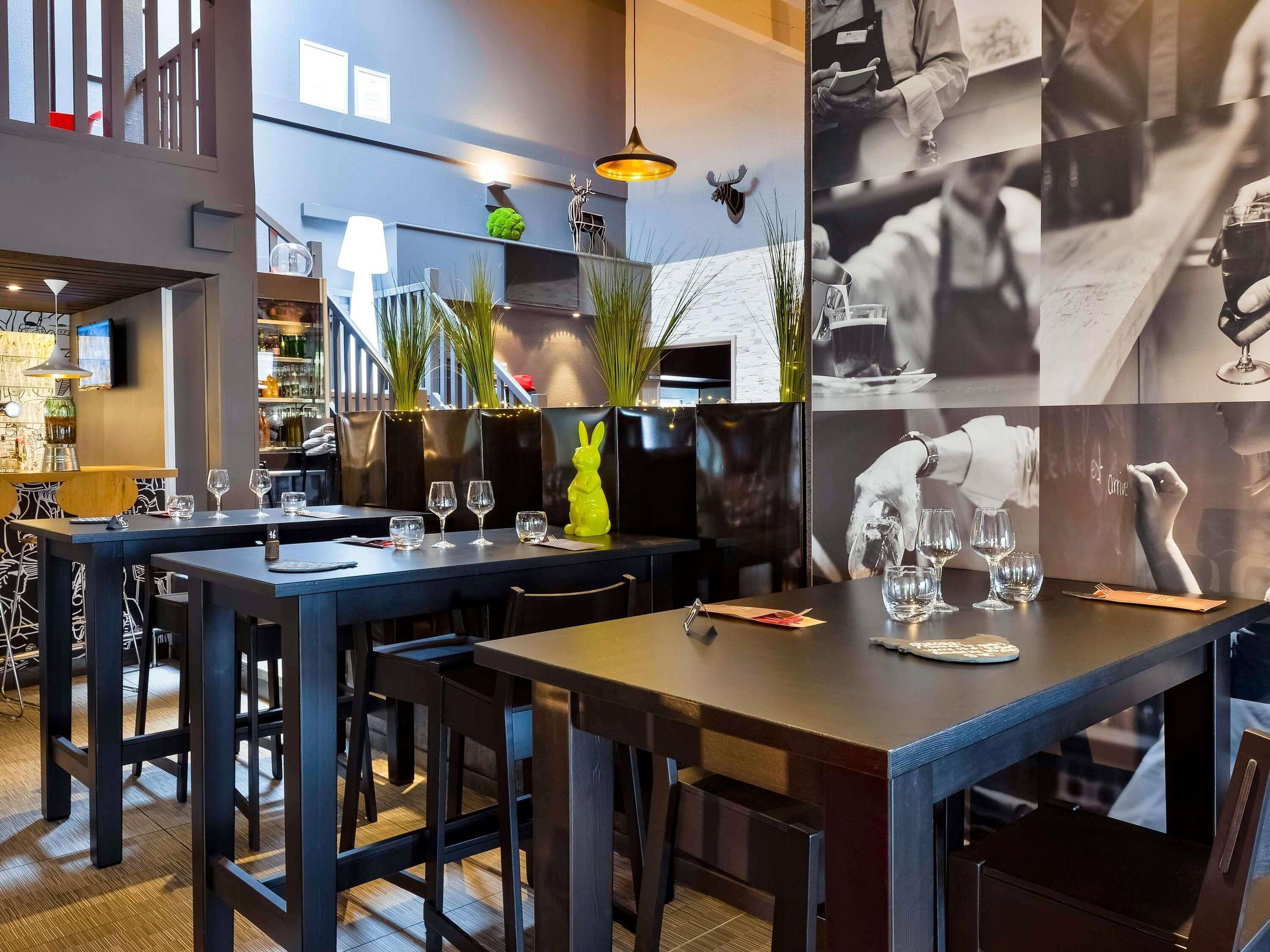 L'intérieur d'un restaurant moderne, avec des tables et des chaises en bois foncé, ainsi qu'un espace bar.