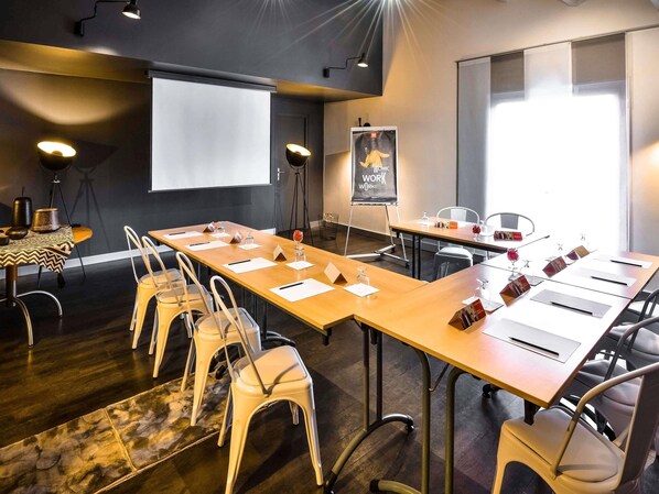A conference room with a long table, chairs, a projector screen, and a whiteboard.
