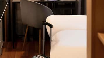 A hotel room with a bed, a desk with a laptop, a chair, and a suitcase.