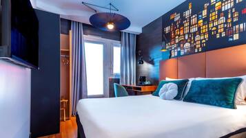 Habitación de hotel moderna con una cama grande, un escritorio y un mural con vista a la ciudad.