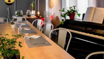 A dining area with a piano, chairs, a table set with plates, glasses, and a plant.
