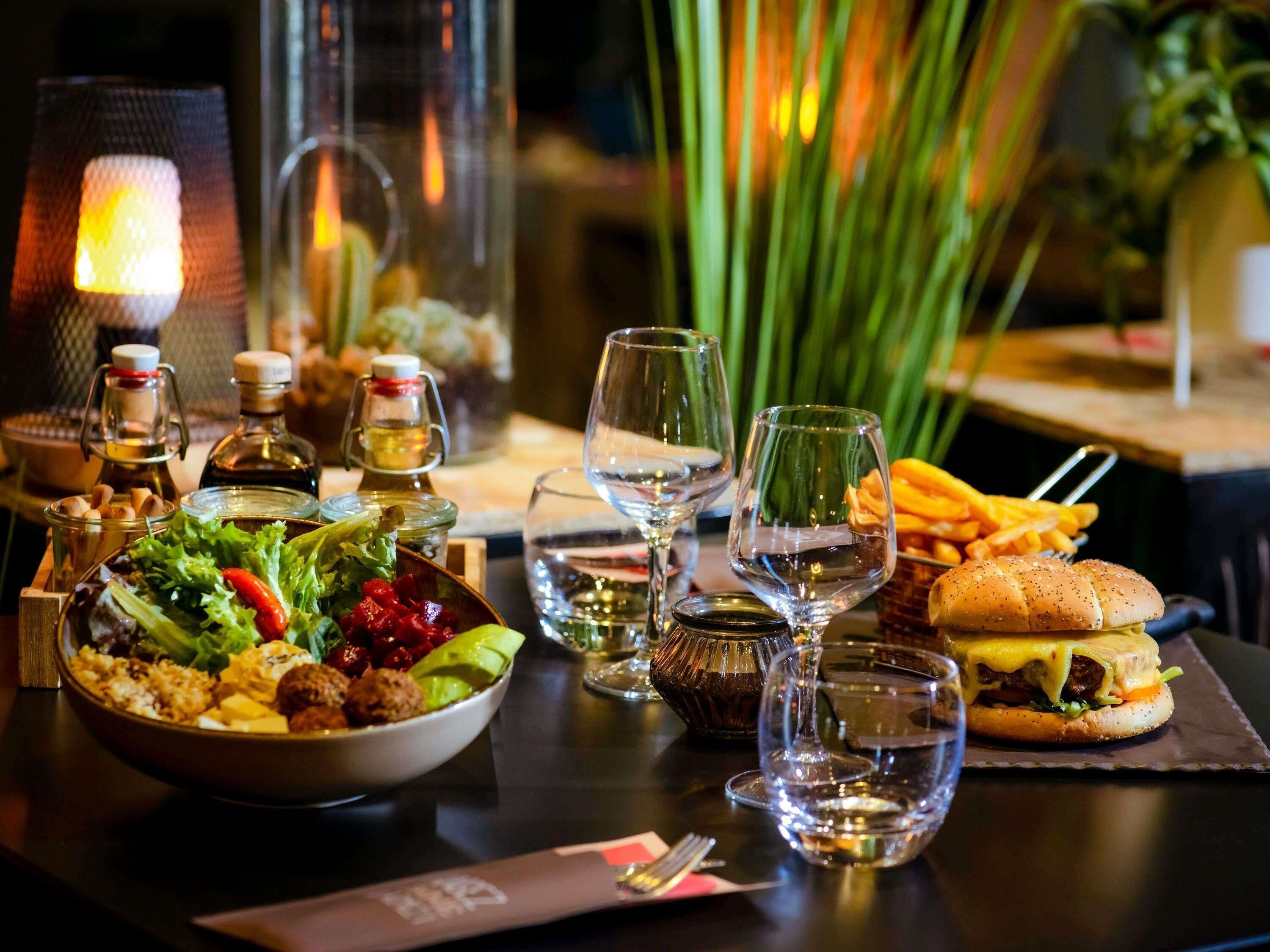 A dining table with a salad, a sandwich, and a bottle of wine.