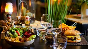 A dining table with a salad, a sandwich, and a bottle of wine.