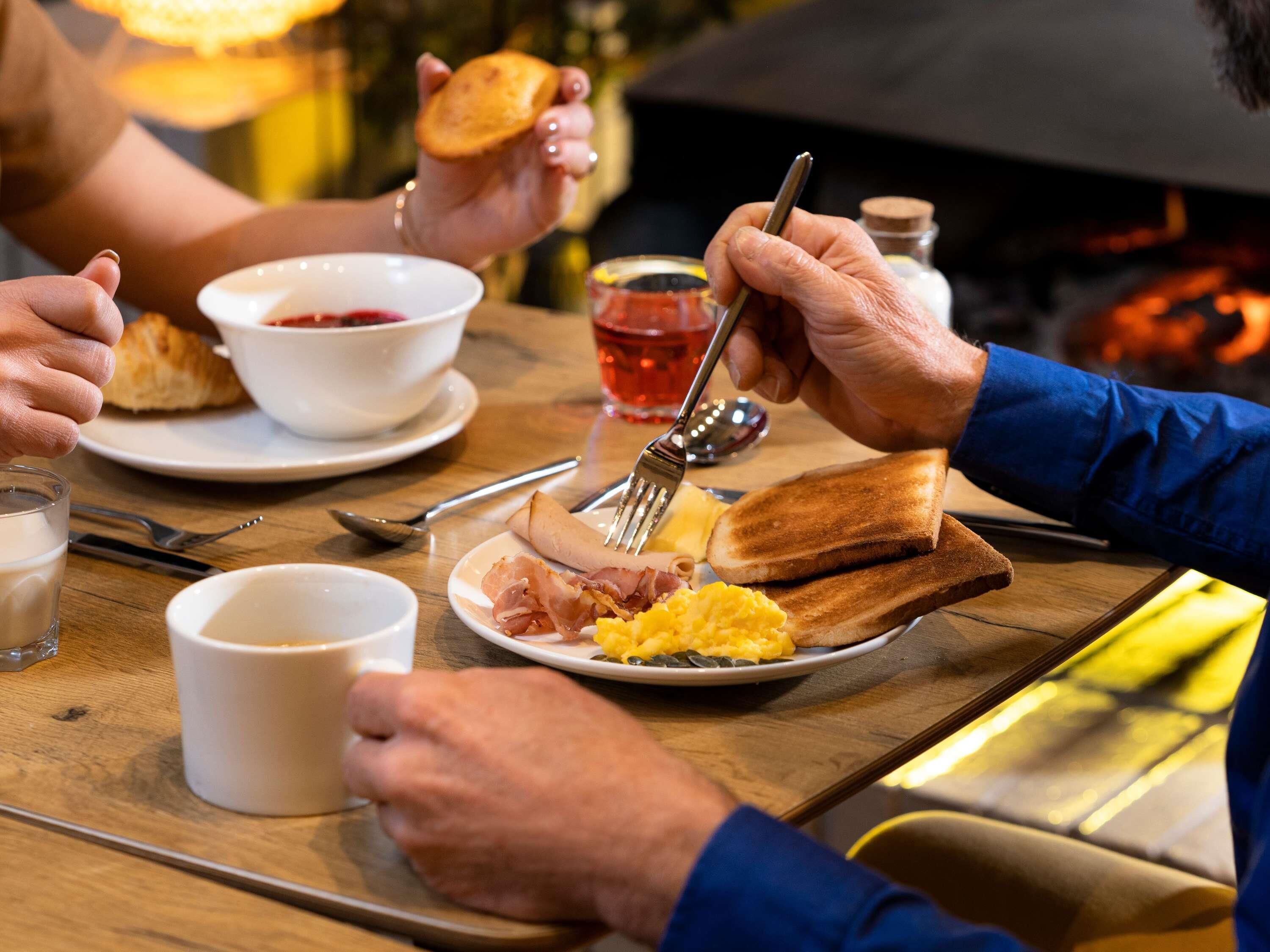 Ein Frühstück mit Toast, Eiern und Schinken auf einem Teller, einer Tasse und einem Glas Saft.