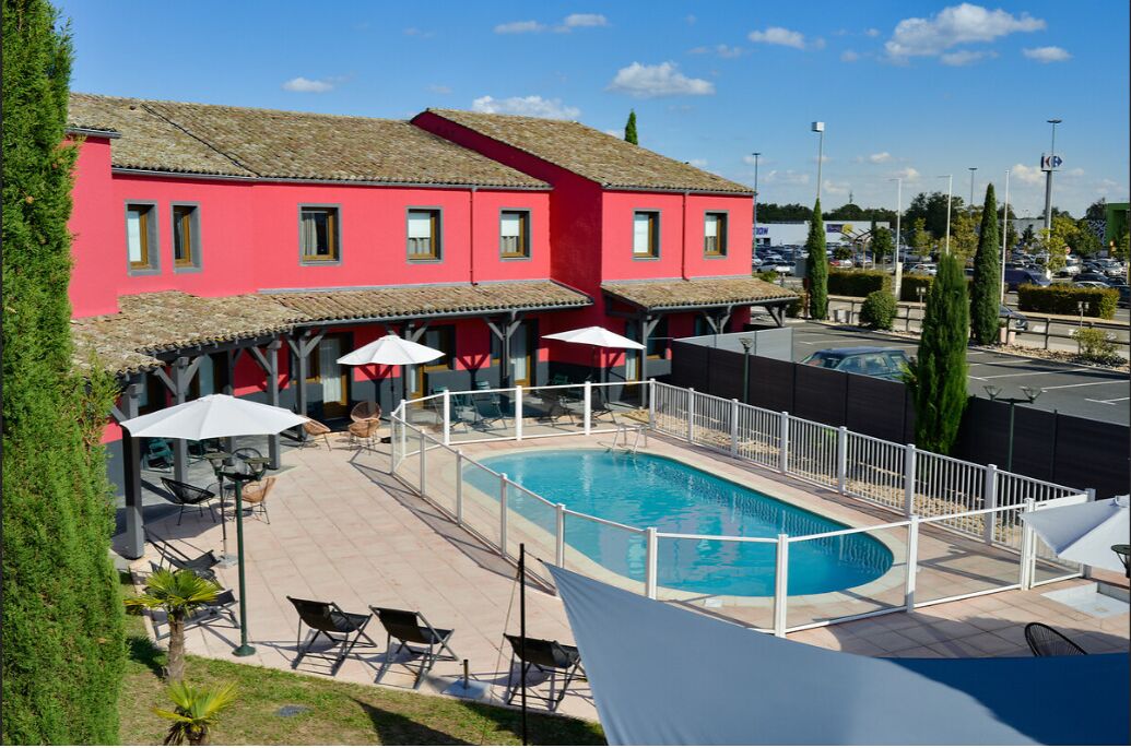 Ein rotes Gebäude mit Schwimmbad, Außenbereich und Parkplatz im Hintergrund.