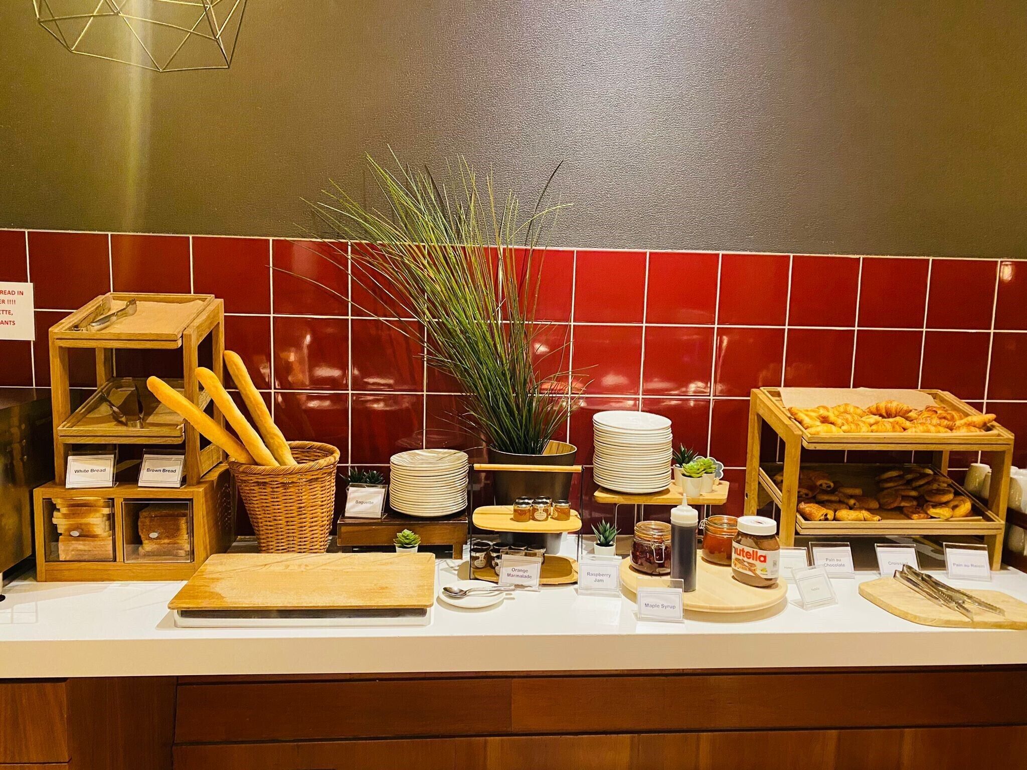 A breakfast buffet with bread, pastries, and condiments.