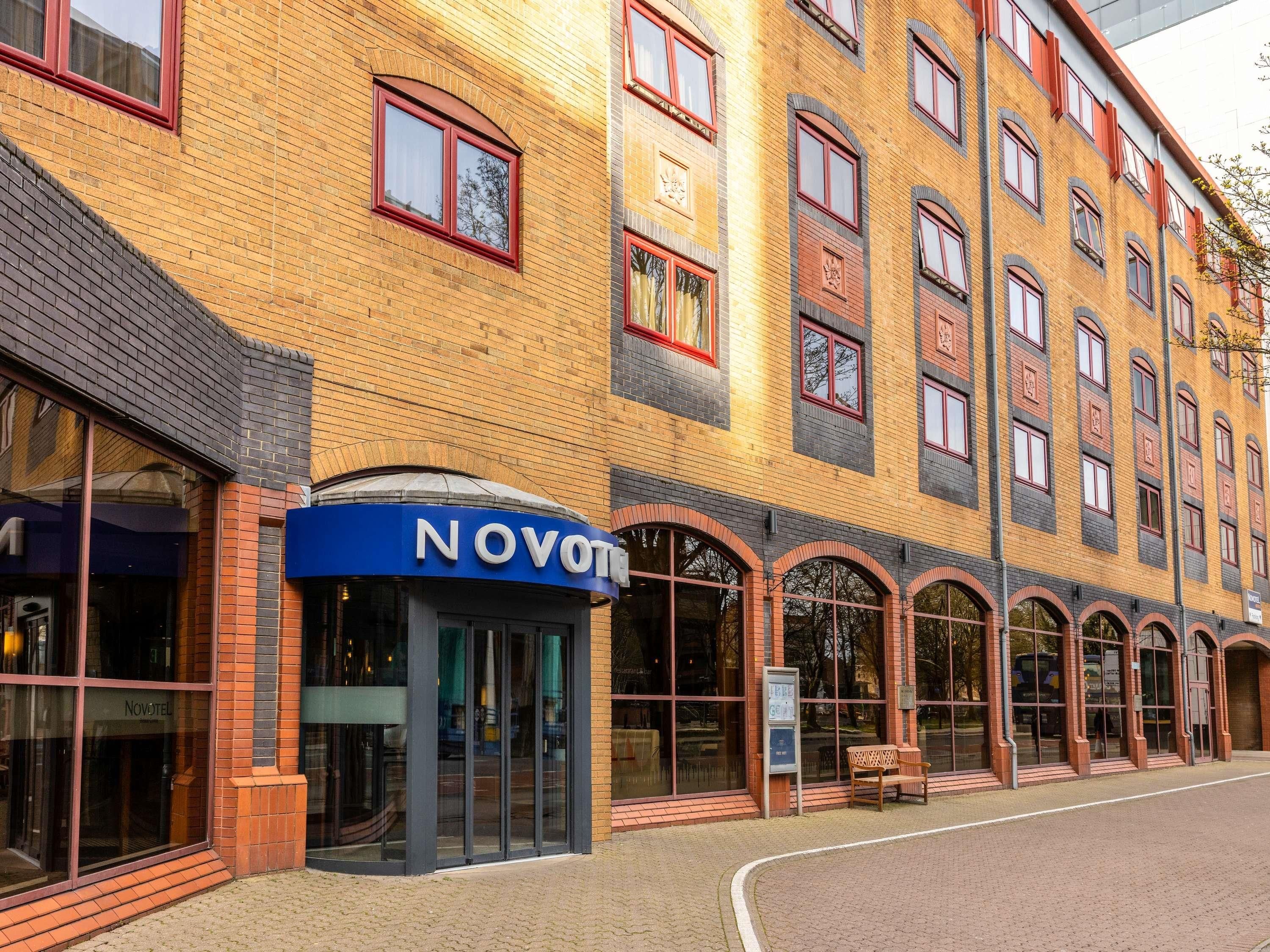 A building with a blue entrance labeled 'NOVOTEL,' large windows, and a brick facade.